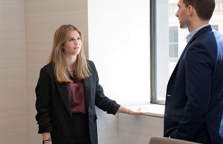 two colleagues standing and talking near window